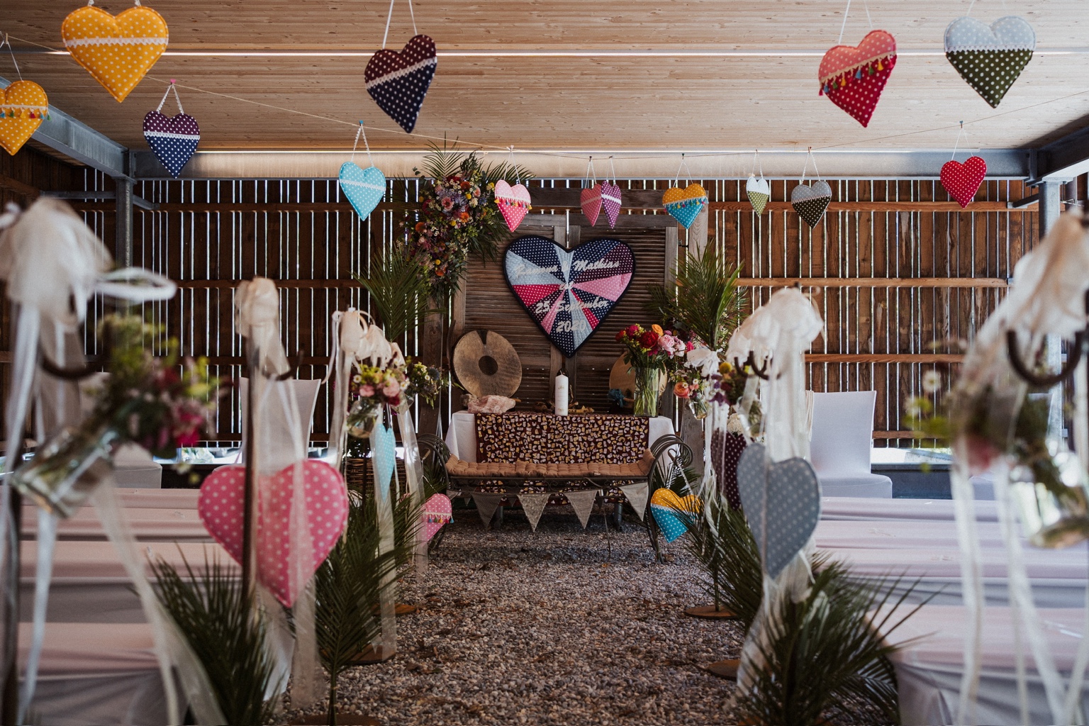 Ramona und Mathias’ Trauungsort: ein Carport mit bunten Stoffherzen unter der Holzdecke